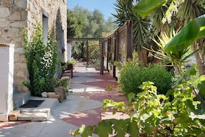 Un edificio de piedra con un sendero de jardín que conduce a una pérgola de madera.