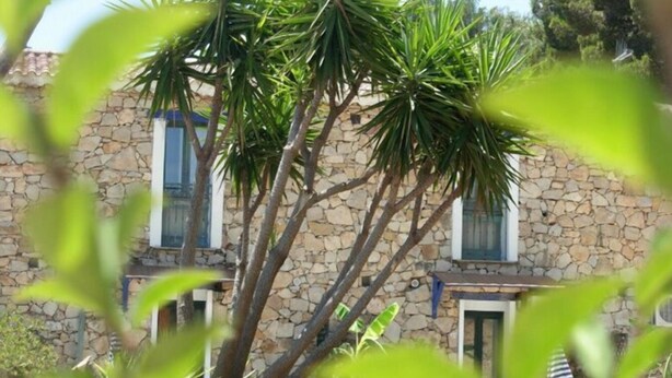 A stone building with a tree in front. - Double room with shared pool and kitchen, Wi-Fi and air conditioning (Gonnesa)