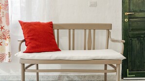 A white bench with a red pillow, a green door, and a white wall with a light switch. - Double room with shared pool and kitchen, Wi-Fi and air conditioning (Gonnesa)