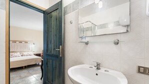 A bathroom with a white sink, a mirror, and a blue door. - Double room with shared pool and kitchen, Wi-Fi and air conditioning (Gonnesa)