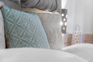 A bed with patterned pillows, a bedside table with a lamp, and a wall-mounted light fixture. - Double room with shared pool and kitchen, Wi-Fi and air conditioning (Gonnesa)