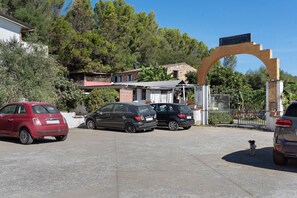 A parking area with several cars, a stone building with a sign, and a large archway. - Double Room with Wi-Fi and Air Conditioning (Gonnesa)