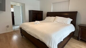 Ein Schlafzimmer mit einem großen Bett, Holzboden, Deckenventilator und einem Kleiderschrank.