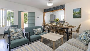Un comedor con una mesa y sillas de madera, un sofá y una mesita con un jarrón de flores.