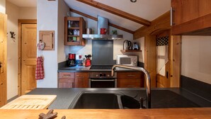 Una cocina con armarios de madera, un lavamanos de acero inoxidable, un microondas y una estufa.
