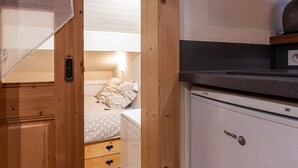 Una habitación pequeña con cama, una kitchenette y una puerta de madera.