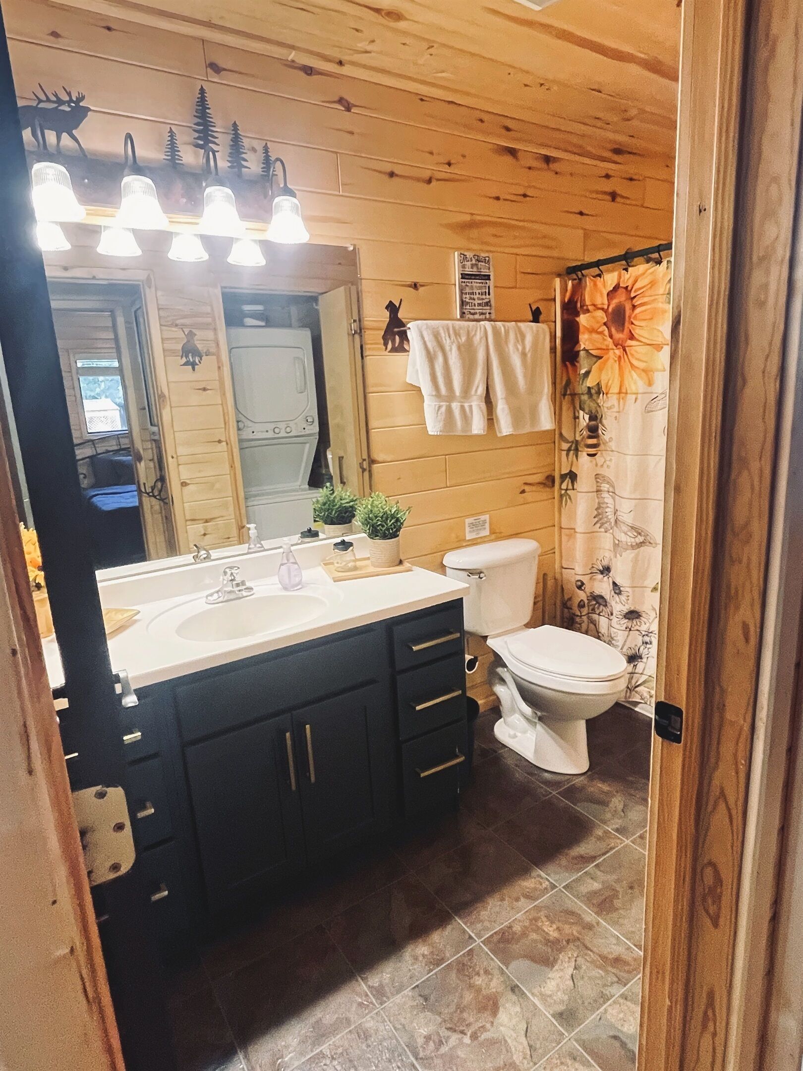 A wooden cabin bathroom with a sink, toilet, and a mirror.