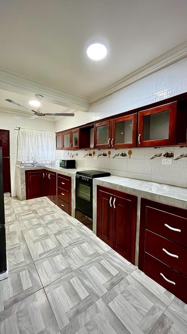 A kitchen with dark wooden cabinets, a white countertop, and a patterned tile floor.