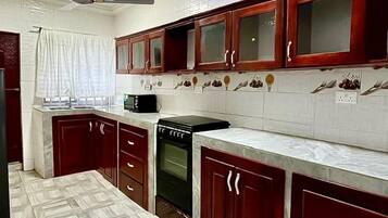 A kitchen with dark wooden cabinets, a white countertop, and a patterned tile floor.