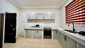 A kitchen with white cabinets, a microwave, a stove, and a sink.