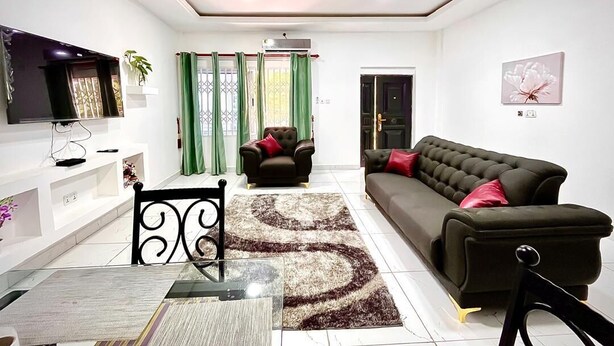 A living room with a sofa, TV, and a dining table with chairs.