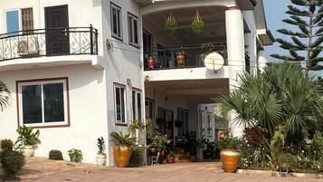 A two-story house with a balcony, potted plants, and a satellite dish.