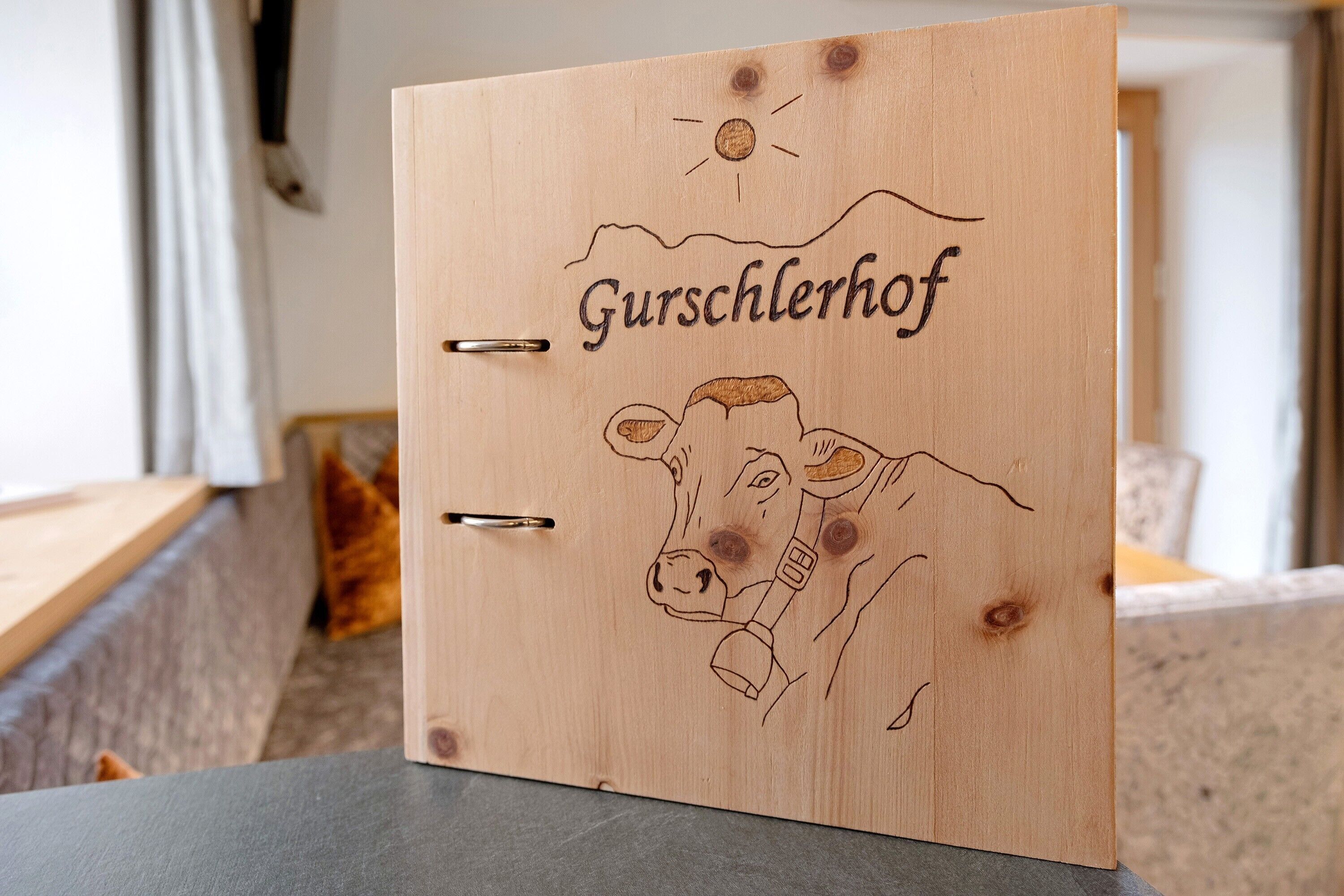 A wooden folder with a cow illustration and the word 'Gusschlerhof' on it.