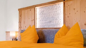 A bed with a wooden headboard, a window with a stone wall, and a lamp on the side. - Apartment 'Morgenrot' with Mountain View, Shared Garden and Wi-Fi (Lasa)