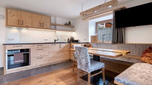 A modern kitchen with wooden cabinets, a built-in oven, and a dining area with a bench and table. - Apartment 'Morgenrot' with Mountain View, Shared Garden and Wi-Fi (Lasa)