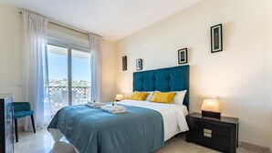 Habitación de hotel con cama, mesita de noche, escritorio y vistas al exterior.
