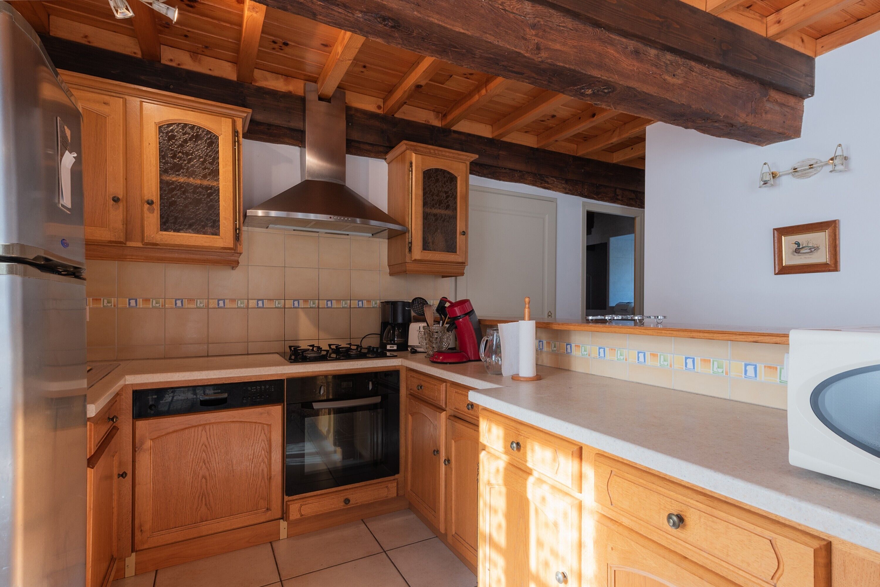 Eine Küche mit Holzausstattung, einer Edelstahl-Dunstabzugshaube und einer gefliesten Rückwand.