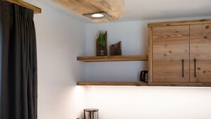 A kitchen with wooden cabinets, a plant on a shelf, and a ceiling light fixture.