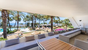 A sunlit outdoor seating area with a pool, palm trees, and a view of the sea. - Apartment 'Parque Miraflores' with Shared Pool, Wi-Fi and Air Conditioning (Mijas)