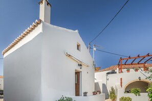 A white building with a tiled roof, a wooden door, and a small window. - Apartment 'Angel’s Studio' with Shared Terrace, Wi-Fi and Air Conditioning (Kithira)