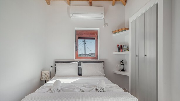 Une chambre à coucher avec un lit, une fenêtre, une armoire et une étagère remplie de livres.