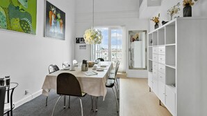 Een eetruimte met een lange tafel, stoelen en een witte kast met lades.
