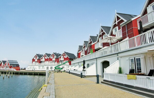 A waterfront property with red and white buildings, a dock, and a gravel walkway.