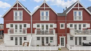 En rødbed og hvid bygning med flere etager, altaner, en veranda og et skilt der viser en restaurant.