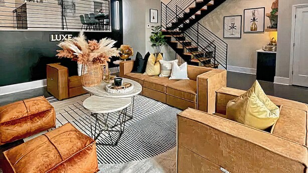 Een moderne woonkamer met een zithoek, een salontafel en een trap.