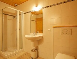 Ein Badezimmer mit Duschkabine aus Glas, Waschbecken mit Spiegel und Toilette.