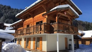 Una cabaña de madera con balcón, rodeada de nieve.