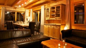 Una habitación acogedora con techo de madera, un sofá de cuero, una mesa de comedor con velas y una zona de cocina.