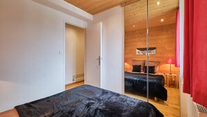 A bedroom with a large bed, a sliding door, and a wooden ceiling.