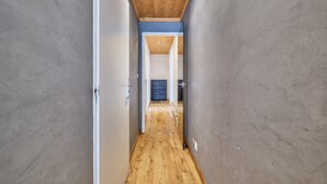 A narrow hallway with wooden flooring, grey walls, and a wooden ceiling.