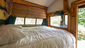 A wooden cabin bedroom with a bed, windows, and a view of trees. - Caravan 'La Pêcherie' with Private Terrace (malbosc)
