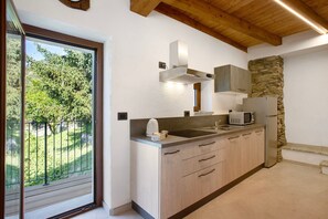 Une cuisine moderne dotée d’une grande fenêtre, de poutres en bois au plafond et d’un mur d’accent en pierre.