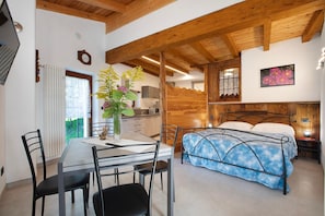 Une pièce comprenant un lit, une table à manger avec des chaises, un coin cuisine et un plafond en bois.