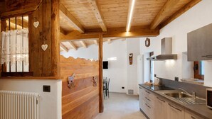 A kitchen with wooden beams, a radiator, a sink, and a window with curtains.