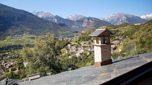 A mountainous landscape with a village, a stone structure, and a clear sky.