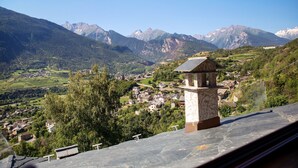 Un paisaje montañoso con un pueblo, una estructura de piedra y un cielo despejado.