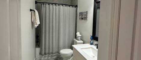 Een badkamer met toilet, wastafel en douchegordijn.