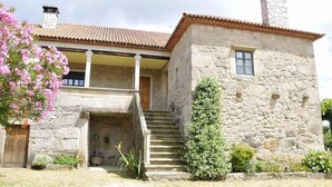 A stone building with a tiled roof, a staircase leading to a door, and a small window. - Country House 'María Bargiela' with Private Terrace, Private Garden and Wi-Fi (A Picaraña)