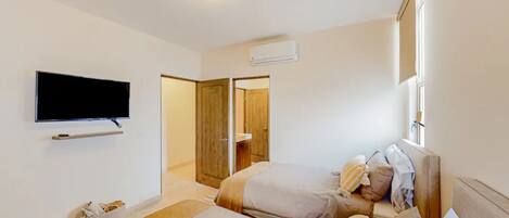 Ein Hotelzimmer mit zwei Betten, einem flachbildfernseher an der Wand, einer Holztür und einem Fenster.