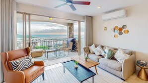 Un amplio salón con un gran ventanal con vistas a un balcón, un ventilador de techo y un diseño de interiores moderno.