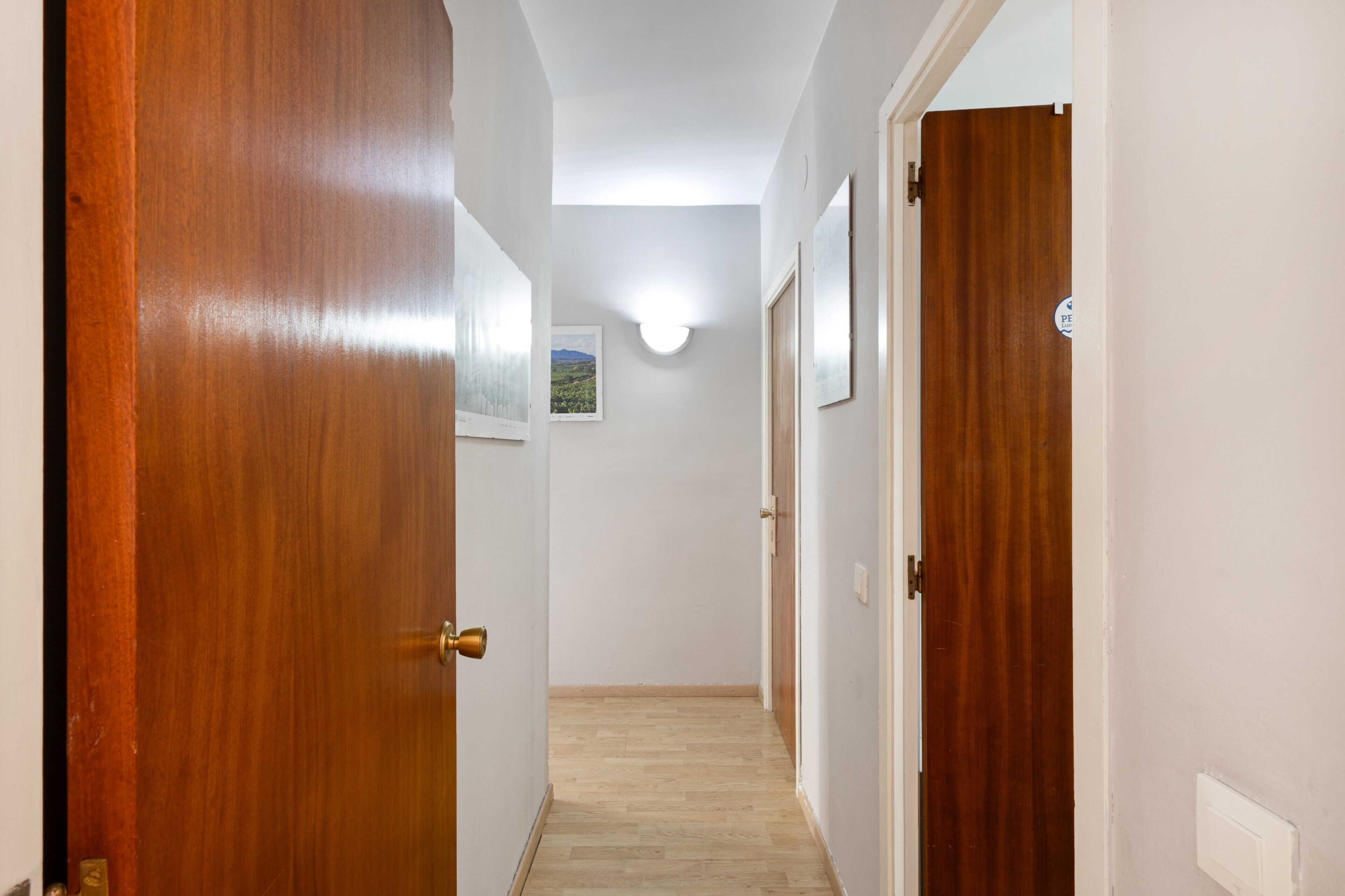 A hallway with wooden doors, a light fixture, and a framed picture on the wall.