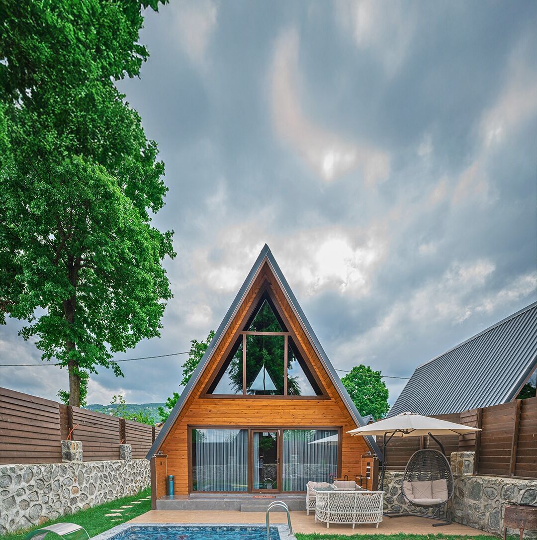 Ein modernes A-Haus mit Swimmingpool, Sitzgelegenheiten im Freien und einer Steinmauer.