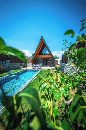 Et moderne hus med swimmingpool, stenvægge og en træterrasse.