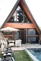 Une maison moderne avec un toit triangulaire, de grandes fenêtres et une piscine.