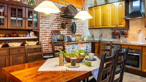 Una cocina con armarios de madera, pared de ladrillo, luces colgantes y una mesa de comedor con sillas.