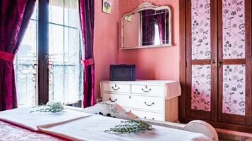 Una habitación con cama, cómoda, espejo y ventana con cortinas.